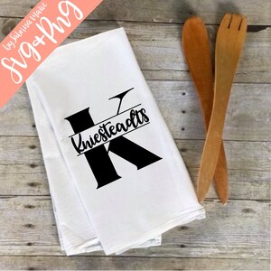 May include: White kitchen towel with a black letter K and the name "Kniestteadts" printed in a script font.