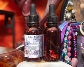 Puede incluir: Dos pequeñas botellas de vidrio con goteros llenas de un líquido rojo y pétalos de rosa. Las botellas están etiquetadas con "Lilith Ritual Oil" y "Belladonna Botanical".