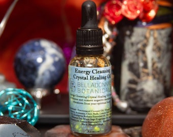 May include: A small glass bottle with a dropper filled with a clear liquid and herbs. The label reads "Energy Cleansing Crystal Healing Oil" and "Belladonnas Botanicals".