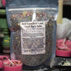 May include: A clear plastic bag filled with a blend of bath salts, herbs, and flowers. The bag is labeled "Self Care/Self Love Ritual Bath Salts BellaDonna's Botanicals". The label also lists the ingredients, which include Dead Sea Salt, Himalayan Salt, Sodium Chloride, Magnesium Sulfate, and various herbs and flowers.
