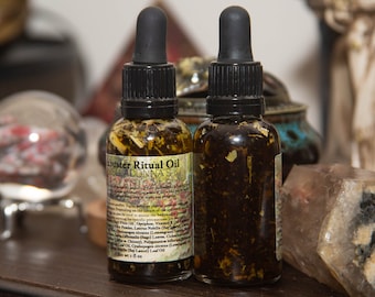 Könnte beinhalten: Zwei kleine bernsteinfarbene Glasflaschen mit Tropfern, gefüllt mit einer dunklen Flüssigkeit und getrockneten Kräutern. Die Flaschen sind mit "Muster Ritual Oil" und "BellaDonna's Botanicals" beschriftet.