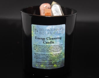May include: Black glass candle jar with a white label that reads "BellaDonna's Botanicals Energy Cleansing Candle". The label has a watercolor background with a floral design. The candle is surrounded by crystals.