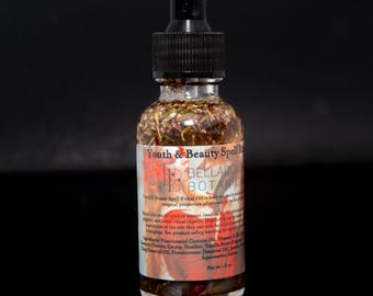 May include: A clear glass bottle with a black dropper top, filled with a liquid containing herbs and flowers. The label reads "Youth & Beauty Spell" and "Belladonna Botanic". The bottle contains 1 fl oz of oil.