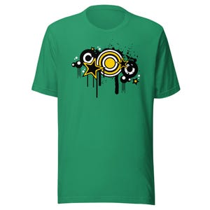 May include: A green t-shirt featuring a black and yellow graphic design with stars, circles, and paint splatters.