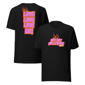 May include: Two black t-shirts with different designs. The first t-shirt has a pink and orange design that says "Love Love Love Me!" The second t-shirt has a pink and orange design that says "Hot Hot Hollywood 626".