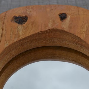 Puede incluir: Un espejo redondo de madera con un acabado de madera natural. El espejo tiene un marco doble con un borde ligeramente elevado. La madera tiene un aspecto r&uacute;stico con nudos y patrones de veta.