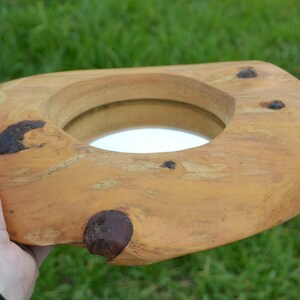 Puede incluir: Un espejo de madera con un acabado de madera natural y un espejo redondo insertado. El espejo est&aacute; rodeado por un marco de madera grueso e irregular.