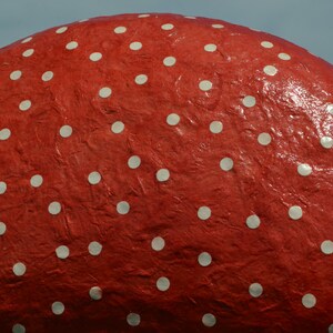 Pu&ograve; includere: Un oggetto rotondo rosso con pois bianchi. La superficie dell'oggetto &egrave; testurizzata e sembra essere fatta di carta.