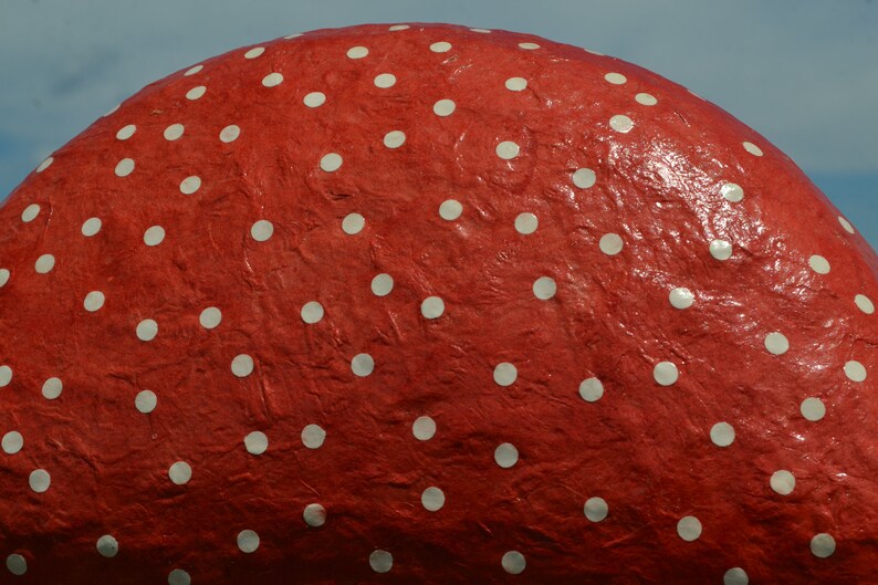 Pu&ograve; includere: Un oggetto rotondo rosso con pois bianchi. La superficie dell'oggetto &egrave; testurizzata e sembra essere fatta di carta.