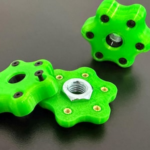 May include: Bright green, star-shaped knobs with black screws and a central hole. One knob is disassembled, revealing a silver nut. The knobs are likely for furniture or machinery, offering a decorative and functional design.