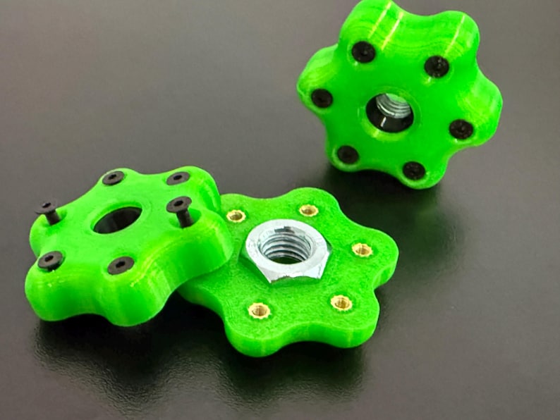 May include: Bright green, star-shaped knobs with black screws and a central hole. One knob is disassembled, revealing a silver nut. The knobs are likely for furniture or machinery, offering a decorative and functional design.