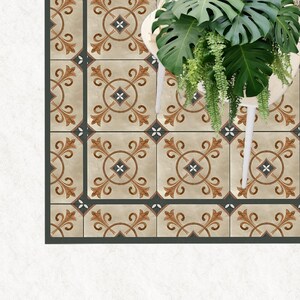 Può includere: Una piastrella per pavimenti beige e marrone con un bordo grigio scuro. La piastrella presenta un motivo ripetitivo di motivi floreali stilizzati e una forma di diamante centrale.
