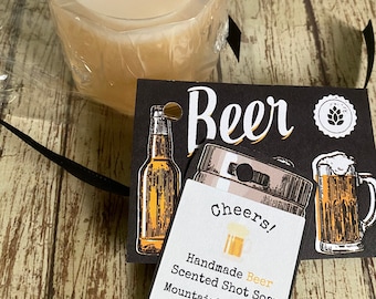 May include: A clear, round, handmade beer-scented shot soap in a glass-like container. The soap is labeled "Cheers! Handmade Beer Scented Shot Soap MountainhouseSoaps Net Wt. 3.5 oz"