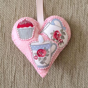 May include: A white ceramic mug with a black handle and the text "But First, Coffee" in a bold, black font. The mug is set against a blurred background, suggesting a cosy setting.