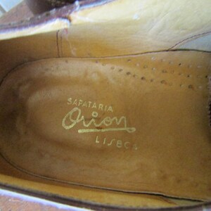 Puede incluir: Primer plano del interior de un zapato de cuero marr&oacute;n con una inscripci&oacute;n dorada que dice "SAPATARIA Orion LISBOA".