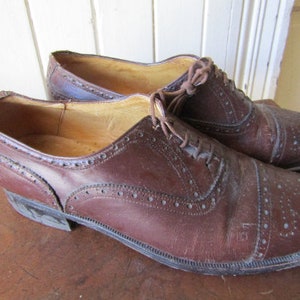 Puede incluir: Un par de zapatos de cuero marr&oacute;n con dise&ntilde;o de punta de ala. Los zapatos tienen cierre de cordones y punta redonda.
