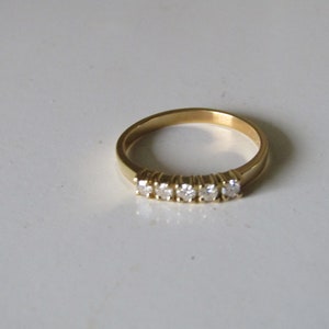 May include: A gold band ring with five small diamonds set in a row.
