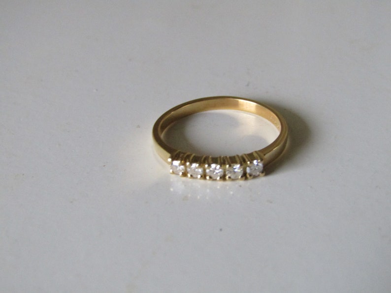 May include: A gold band ring with five small diamonds set in a row.