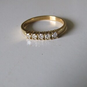 May include: A gold band ring with five small diamonds set in a row.