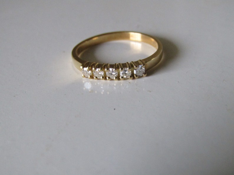 May include: A gold band ring with five small diamonds set in a row.