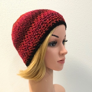 May include: A red and black crocheted beanie with a gradient of color from dark red to light red.