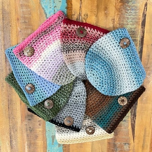 May include: A set of seven crocheted pouches in various colors, including pink, blue, green, brown, and gray. Each pouch has a wooden button closure.