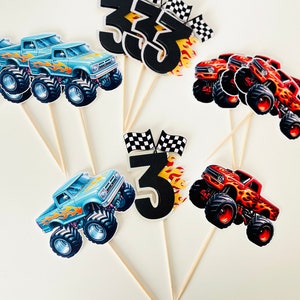 May include: Set of six monster truck cake toppers. The toppers feature blue and red monster trucks with flames, and black numbers 3 and 33 with checkered flags.