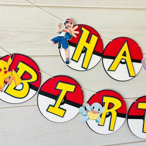 K&ouml;nnte beinhalten: Ein dekoratives Banner mit kreisf&ouml;rmigen Ausschnitten, die wie rot-wei&szlig;e Pok&eacute;-B&auml;lle gestaltet sind. Jeder Kreis zeigt einen gro&szlig;en gelben Buchstaben, die zusammen HAPPY BIRTH ergeben, erg&auml;nzt durch bunte Illustrationen von Pikachu, Ash Ketchum, Mewtu und Schiggy.