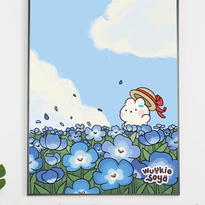 Puede incluir: Una impresión artística enmarcada que presenta una ilustración caprichosa de un personaje parecido a una nube con un sombrero de paja con una cinta roja, de pie en un campo de flores azules bajo un cielo azul con nubes. Incluye el texto "Wuykie Soya".