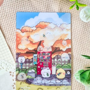 May include: A colorful illustration of a vending machine in a park setting. The artwork features cartoon characters, a red vending machine, and a tree with orange and yellow leaves. The sky is blue with fluffy clouds.