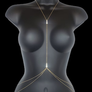 May include: A gold body chain with multiple strands and clear crystal accents.