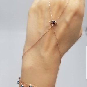 May include: A gold chain bracelet with a blue evil eye charm. The bracelet is layered with multiple strands of chain and features several smaller blue evil eye charms.