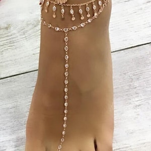 May include: A gold anklet with a turquoise beaded anklet and a shell charm. The anklet is layered with a delicate chain with small crystals.