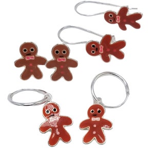 May include: Set of three gingerbread man earrings. Two earrings are silver with a gingerbread man charm. The third earring is a silver hoop with a gingerbread man charm.
