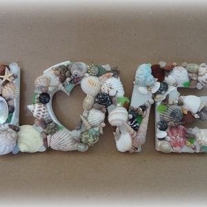 Sinal de AMOR em concha e vidro do mar