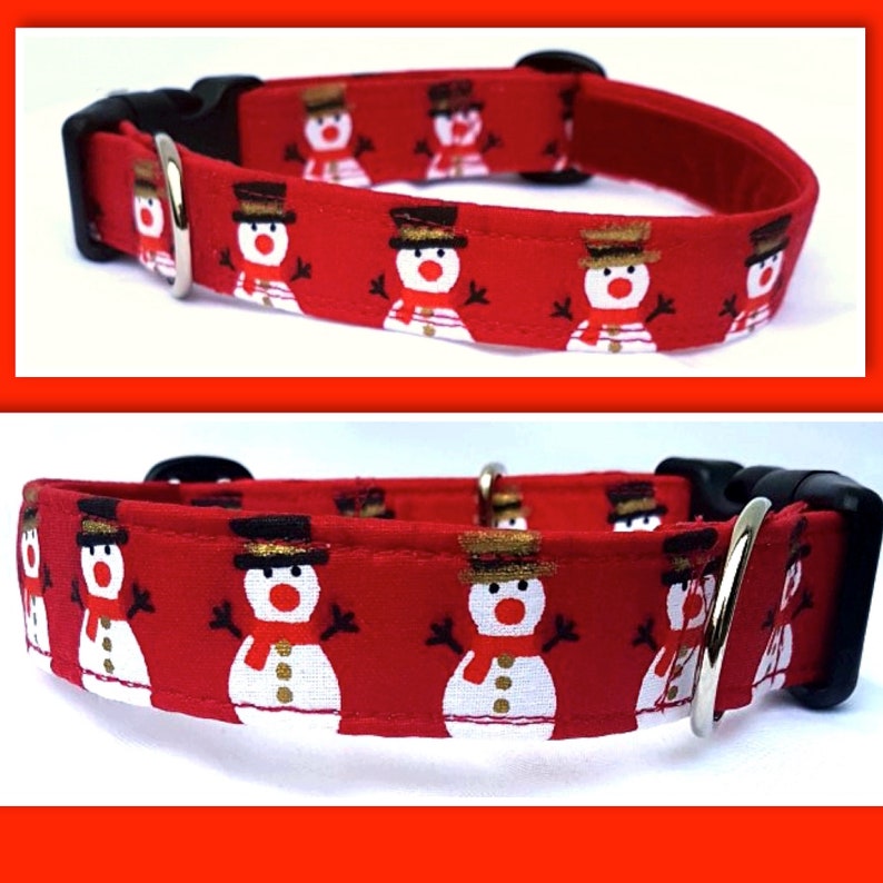 May include: A red pet collar featuring a repeating pattern of white snowmen with black top hats, orange noses, and red scarves. The collar includes a black plastic side-release buckle and a silver-toned metal D-ring for attaching a leash.