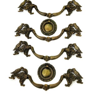 Può includere: Set di quattro tiretti per armadi in ottone antico con motivi di uccelli e fiori decorativi. Ogni tiretto è dotato di una maniglia ad anello e di una piastra posteriore decorativa.