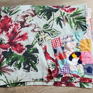 Peut inclure: Un tissu à motif floral vert et rouge avec une courtepointe en patchwork cousue dessus. La courtepointe est faite de différentes couleurs et motifs, dont le rouge, le bleu, le jaune et le blanc.