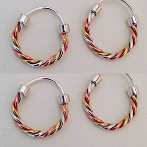 Puede incluir: Cuatro pendientes de aro de plata con un diseño trenzado de plata, oro y cobre.