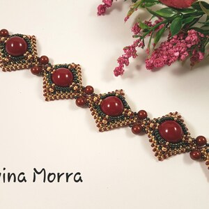 Peut inclure: Un bracelet en perles avec un motif g&eacute;om&eacute;trique compos&eacute; de perles rouges, dor&eacute;es et vertes. Le bracelet a un fermoir carr&eacute; et est orn&eacute; de perles de pierres pr&eacute;cieuses rouges.