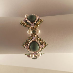 Peut inclure: Un bracelet en perles vertes et dor&eacute;es avec deux grandes pierres vertes et des perles blanches.