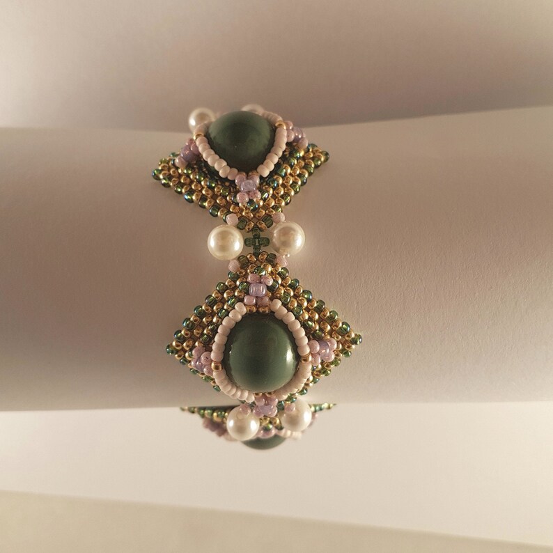 Peut inclure: Un bracelet en perles vertes et dor&eacute;es avec deux grandes pierres vertes et des perles blanches.