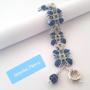 May include: A blue and silver beaded bracelet with a floral design. The bracelet has a silver clasp and a blue bead at the end.