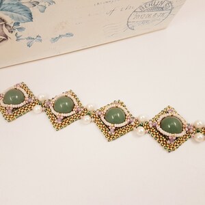 Peut inclure: Un bracelet en pierres pr&eacute;cieuses vertes avec des perles dor&eacute;es et roses. Le bracelet pr&eacute;sente un motif r&eacute;p&eacute;titif de perles carr&eacute;es avec une pierre pr&eacute;cieuse verte au centre.
