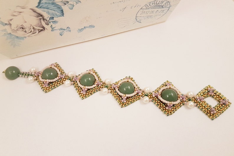 Peut inclure: Un bracelet en pierres pr&eacute;cieuses vertes avec des perles dor&eacute;es et roses. Le bracelet pr&eacute;sente un motif r&eacute;p&eacute;titif de perles carr&eacute;es avec une pierre pr&eacute;cieuse verte au centre.