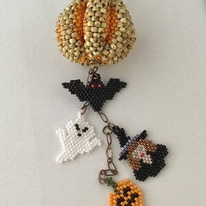 May include: A beaded necklace with a pumpkin charm, a bat charm, a ghost charm, a witch charm, and a jack-o'-lantern charm.