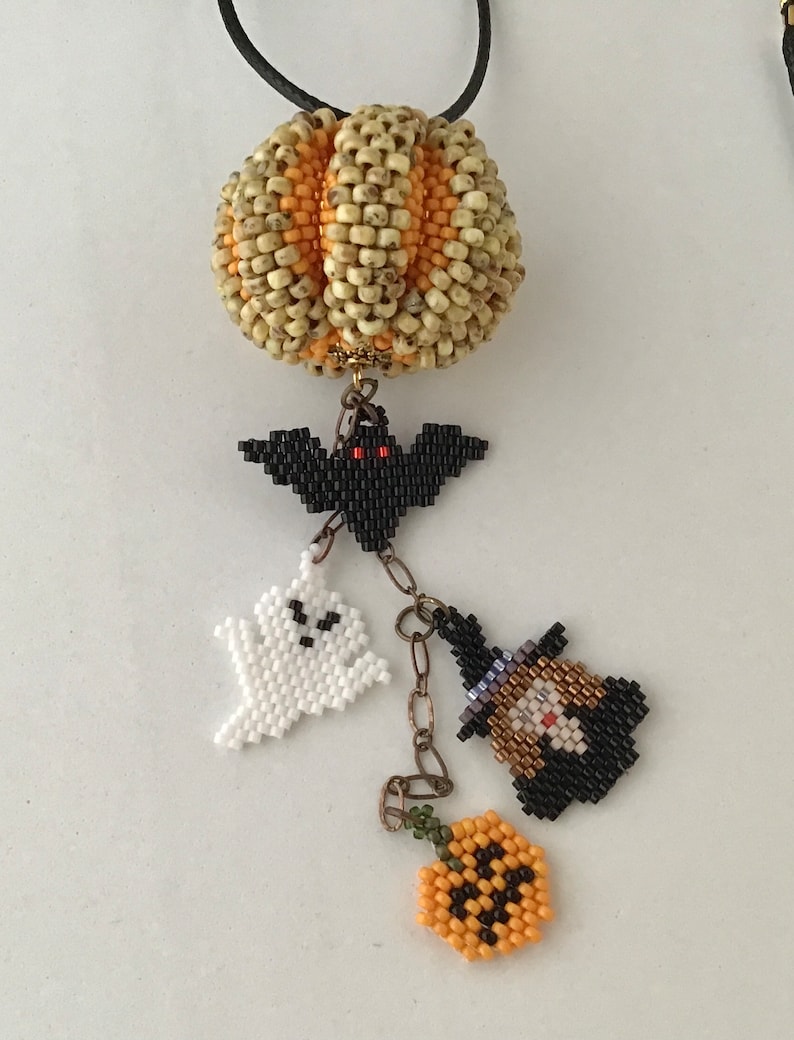 May include: A beaded necklace with a pumpkin charm, a bat charm, a ghost charm, a witch charm, and a jack-o'-lantern charm.