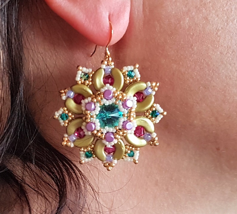 以下が含まれることがあります： 緑、紫、赤のビーズで花柄のデザインが施されたゴールドのイヤリング。花の真ん中には大きなターコイズ色の宝石が埋め込まれています。