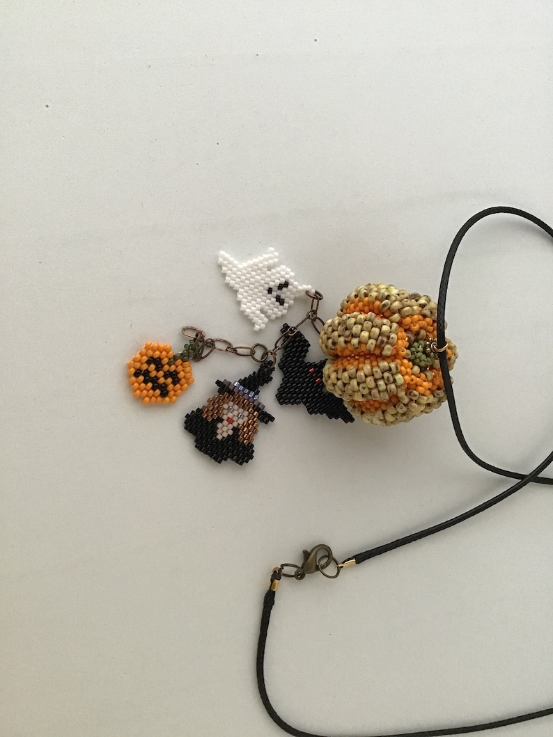 May include: A black beaded necklace with a variety of Halloween-themed charms, including a pumpkin, a ghost, a witch, and a bat.