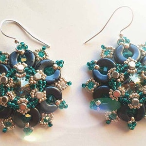 以下が含まれることがあります： 黒と緑のビーズでデザインされた、ぶら下がりのイヤリングのペア。イヤリングは、中央にクリスタルが埋め込まれた、大きく丸いビーズのセンターピースが特徴です。